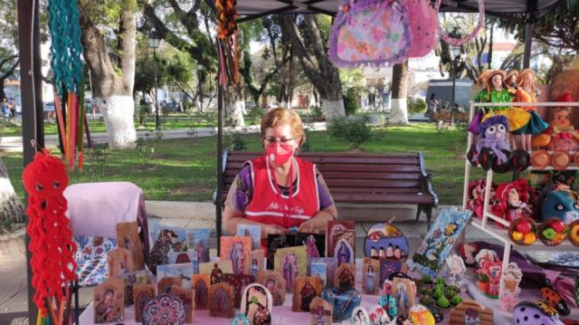 Roxana Menéndez con sus pinturas y muñequería.