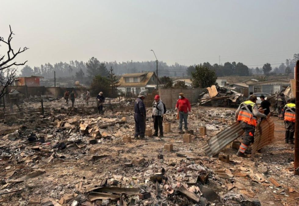 Habitantes del sur de Chile, caminan entre los restos de sus viviendas alcanzadas por un incendio